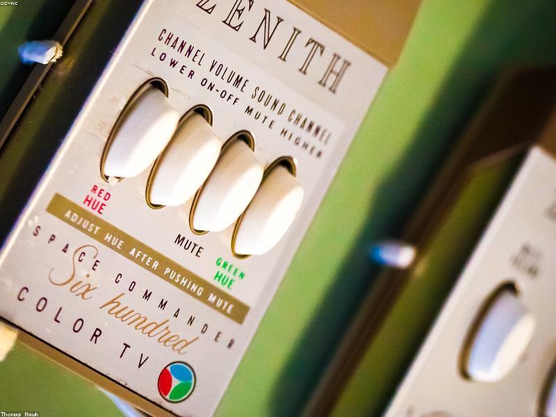 Photorealistic image of a modern German living room with a large 65-inch 4K Smart TV displaying the Waipu.tv interface with colorful channel logos, warm ambient lighting, contemporary furniture, and a remote control in the foreground, tech-style aesthetic with blue and white color grading